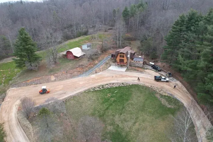 A graded loop drive below a house, with a roller, seen from the air