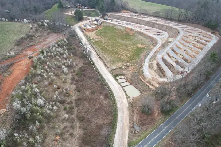 A graded drive beside a terraced field, before paving, seen from the air