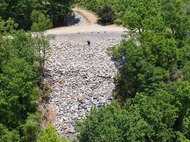 A rebuilt rock slope below a road, seen from the air