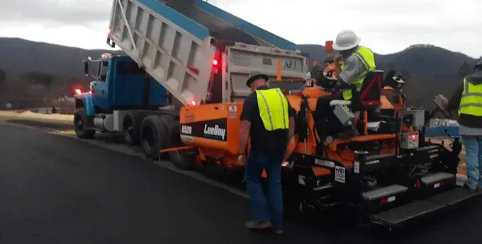 A dump truck feeding asphalt into a paver