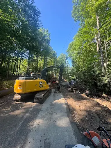 An excavator working along a drive in the woods
