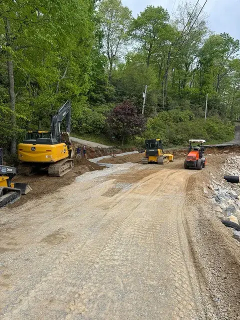 An excavator and loaders grading a dirt road