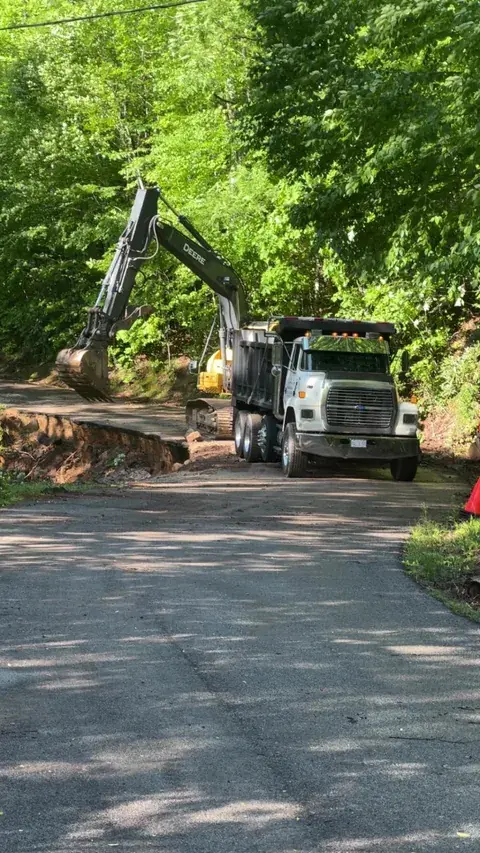 An excavator and dump truck on a paved road