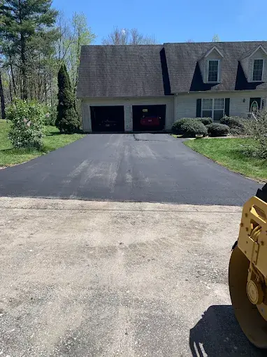 A finished asphalt driveway in front of a house