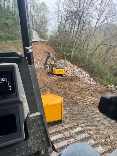 An excavator working a hillside, seen from a machine cab