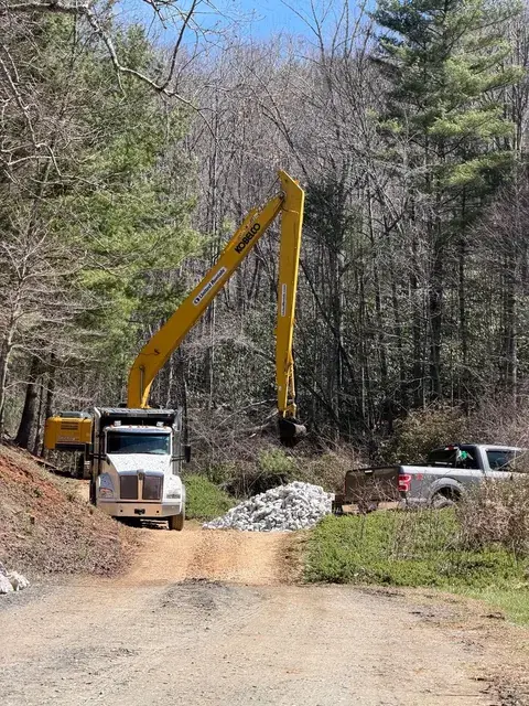 A long-reach excavator working beside a dump truck