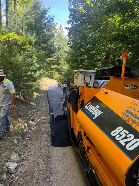 A paver laying asphalt on a narrow drive