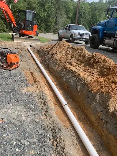 White pipe laid in a trench beside a gravel drive