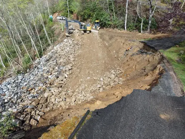 Rock placed on a slid road bank while an excavator works above