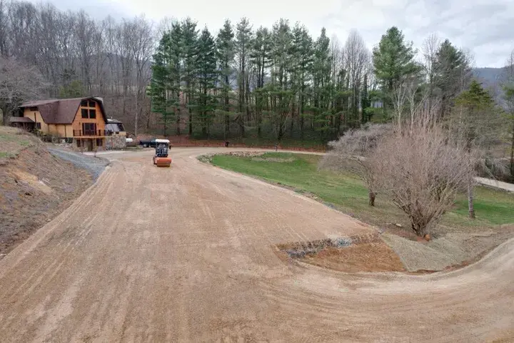 A roller on a graded drive in front of a house