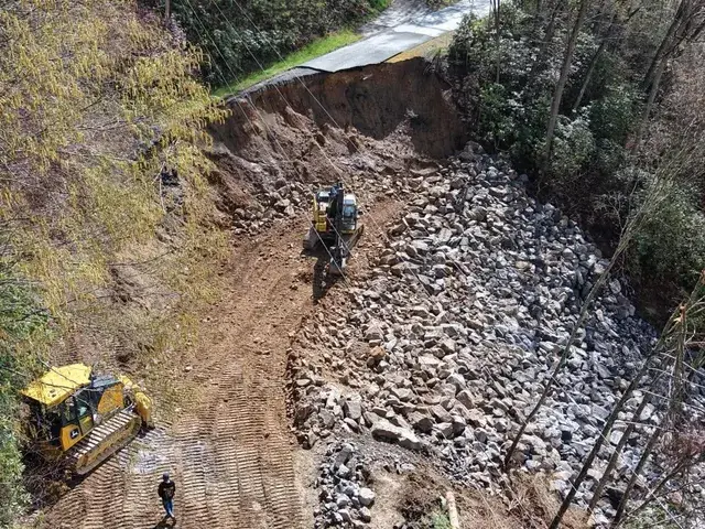 Equipment rebuilding a slid slope with rock