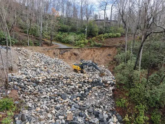 An excavator rebuilding a slid slope with rock