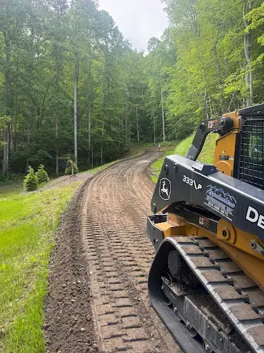 A track loader grading a dirt drive
